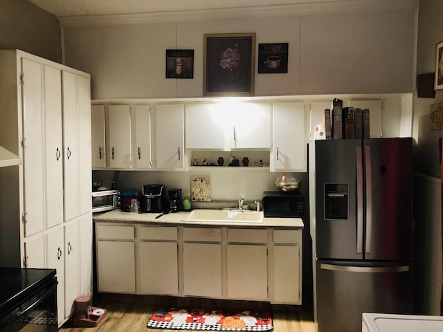 kitchen featuring stainless steel fridge, white cabinetry, and sink