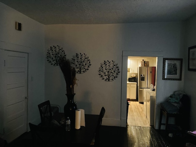 dining space with light wood-type flooring and a textured ceiling