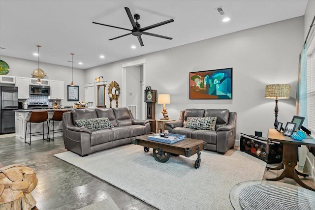 living room featuring ceiling fan and concrete flooring