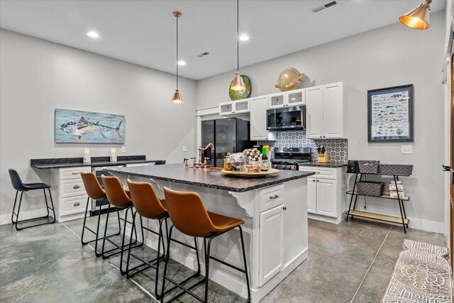 kitchen with a center island with sink, white cabinets, a breakfast bar area, decorative backsplash, and stainless steel appliances