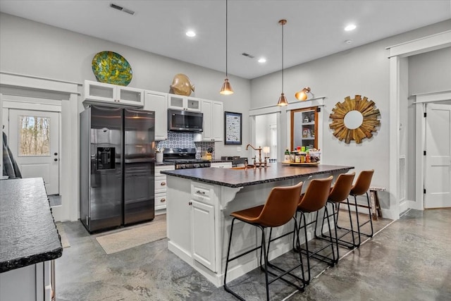 kitchen featuring white cabinets, black fridge with ice dispenser, backsplash, and an island with sink