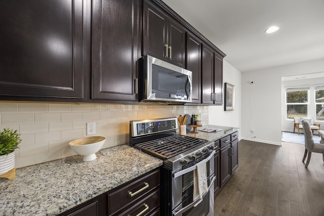 kitchen featuring dark wood-type flooring, stainless steel appliances, dark brown cabinetry, light stone counters, and decorative backsplash