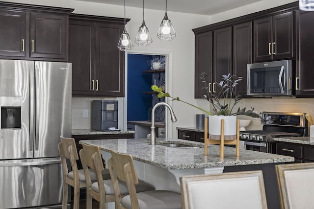 kitchen with stainless steel appliances, dark brown cabinets, sink, and a kitchen island with sink