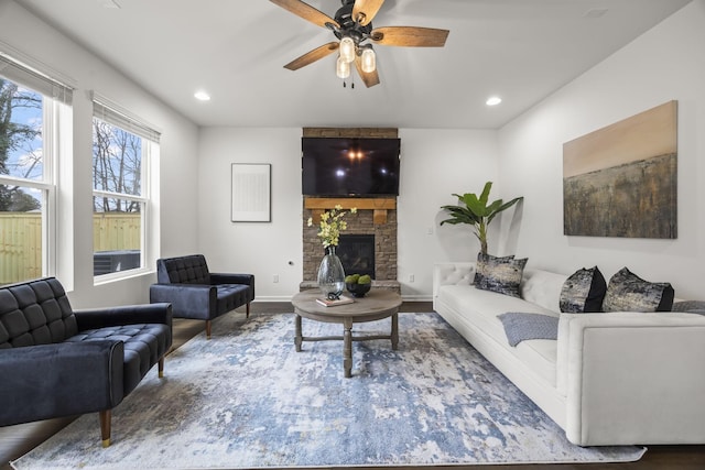 living room with hardwood / wood-style floors, a stone fireplace, and ceiling fan