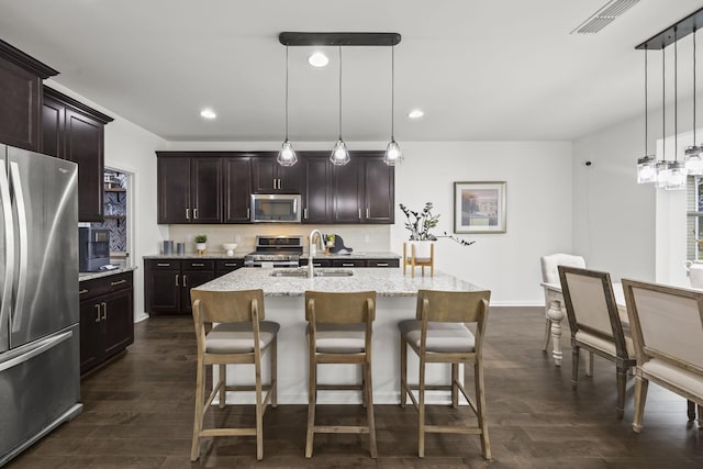 kitchen featuring appliances with stainless steel finishes, sink, a center island with sink, and decorative light fixtures