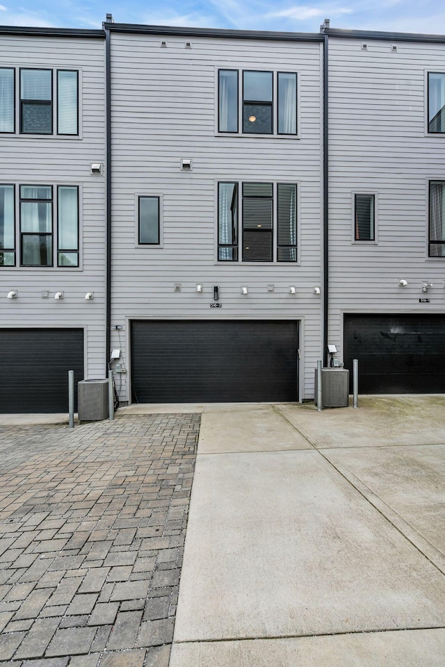 rear view of house with central AC unit and a garage