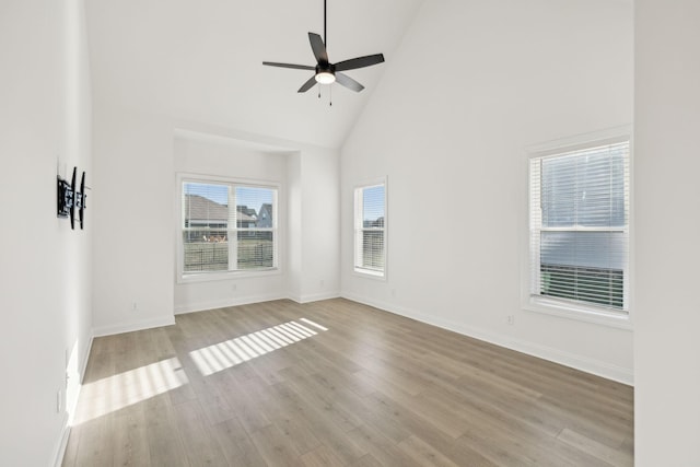 spare room with ceiling fan, light hardwood / wood-style flooring, high vaulted ceiling, and a healthy amount of sunlight