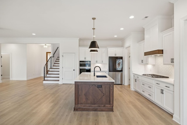 kitchen featuring backsplash, stainless steel appliances, sink, white cabinetry, and hanging light fixtures