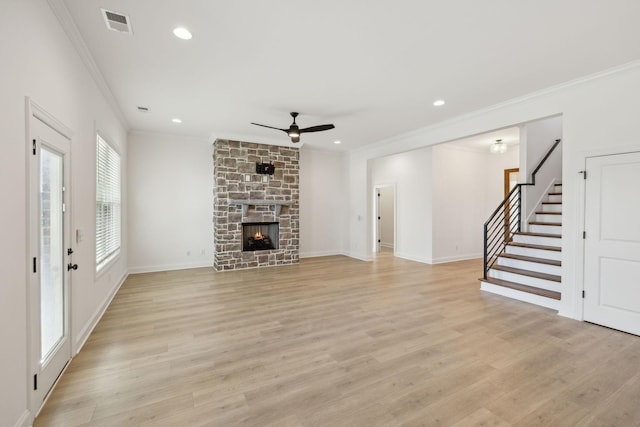 unfurnished living room featuring ceiling fan, crown molding, a fireplace, and light hardwood / wood-style flooring