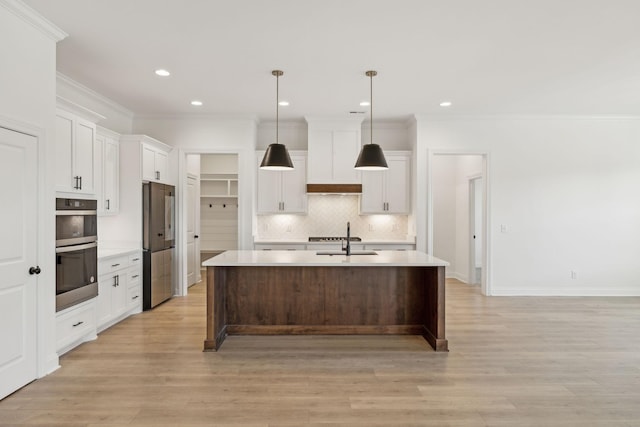 kitchen featuring white cabinets, pendant lighting, appliances with stainless steel finishes, and an island with sink