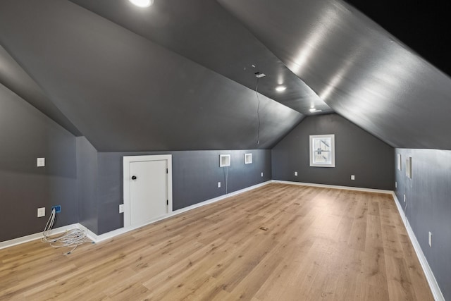 additional living space featuring vaulted ceiling and light hardwood / wood-style flooring