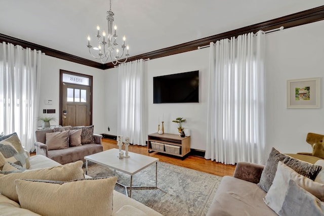 living room with ornamental molding, a chandelier, and light hardwood / wood-style floors