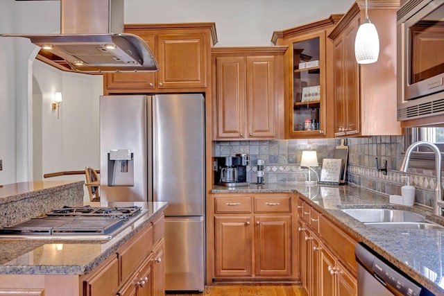 kitchen with exhaust hood, sink, decorative backsplash, light stone countertops, and appliances with stainless steel finishes