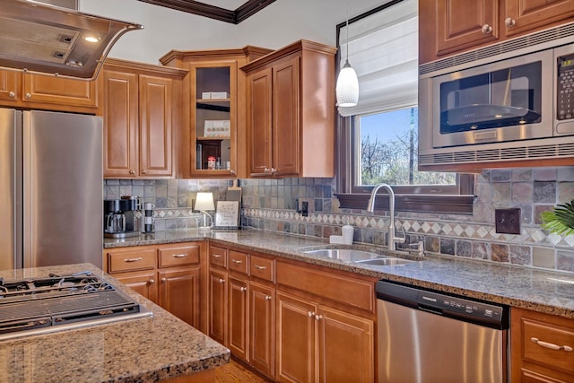 kitchen featuring light stone countertops, sink, stainless steel appliances, crown molding, and decorative light fixtures