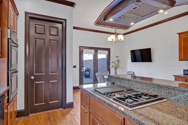 kitchen with crown molding, light stone countertops, stainless steel appliances, and an inviting chandelier