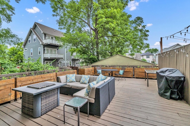 wooden terrace featuring grilling area and an outdoor living space with a fire pit