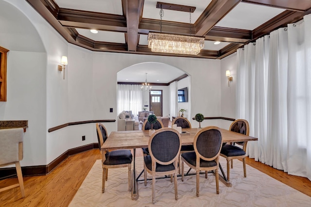 dining space with beam ceiling, light hardwood / wood-style flooring, crown molding, and coffered ceiling