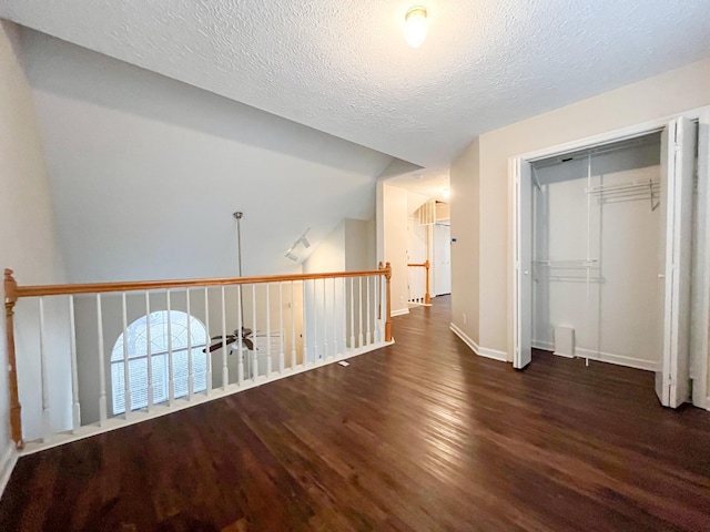 hall featuring a textured ceiling and dark hardwood / wood-style floors