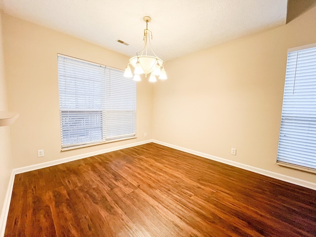 unfurnished room with a chandelier, a textured ceiling, and wood-type flooring