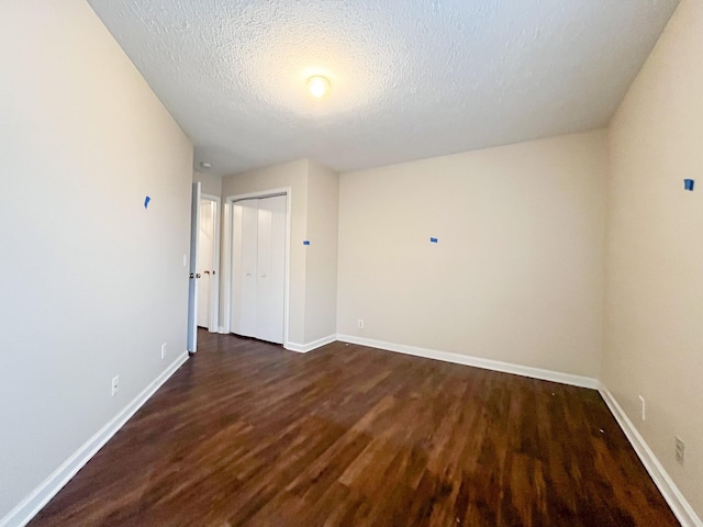 unfurnished room featuring a textured ceiling and dark wood-type flooring