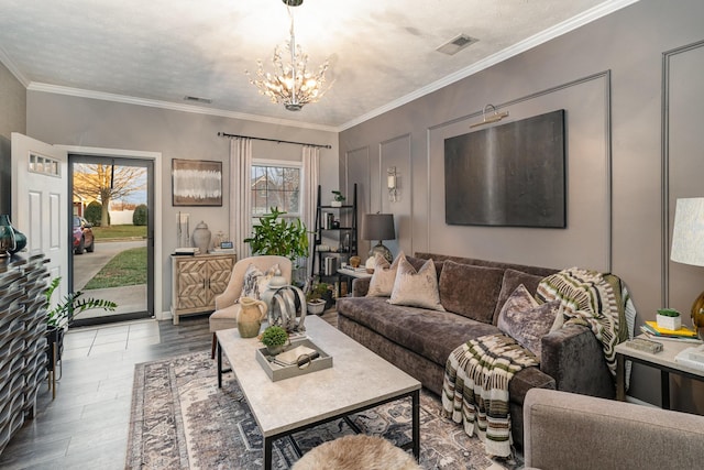 living room featuring hardwood / wood-style floors, a textured ceiling, crown molding, and a notable chandelier