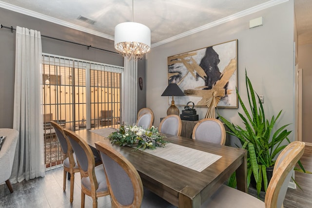 dining room with hardwood / wood-style flooring, an inviting chandelier, and ornamental molding