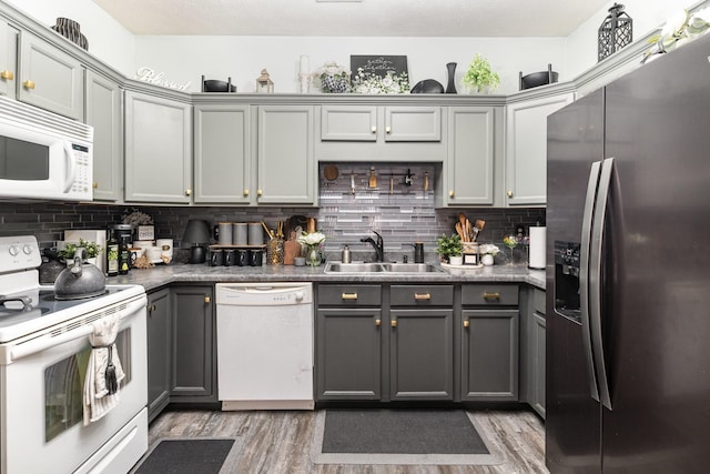 kitchen featuring white appliances, backsplash, gray cabinets, and sink