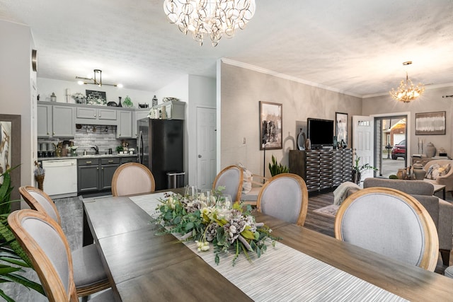 dining room with hardwood / wood-style flooring, a textured ceiling, an inviting chandelier, ornamental molding, and sink