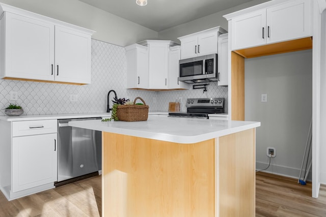 kitchen featuring light wood-type flooring, appliances with stainless steel finishes, a center island, and white cabinetry