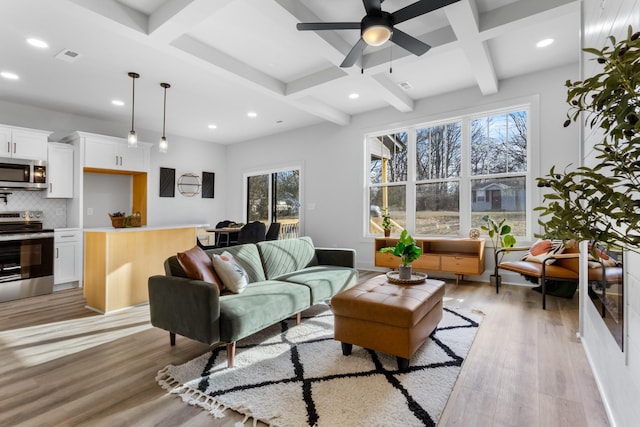 living room featuring ceiling fan, beamed ceiling, light hardwood / wood-style floors, and coffered ceiling