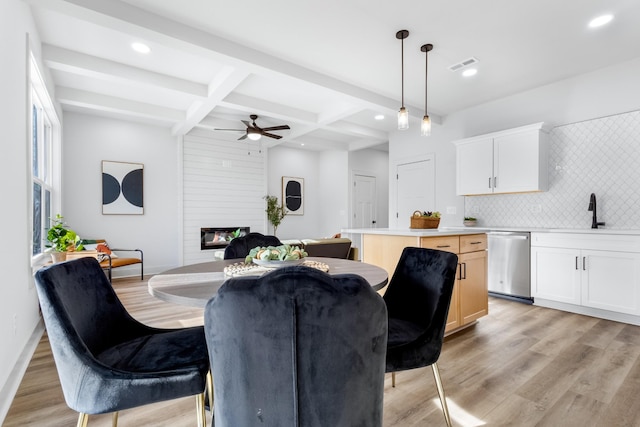 dining room with beam ceiling, ceiling fan, sink, and light hardwood / wood-style floors