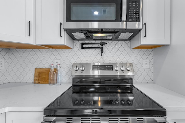 kitchen with tasteful backsplash, white cabinetry, light stone countertops, and appliances with stainless steel finishes