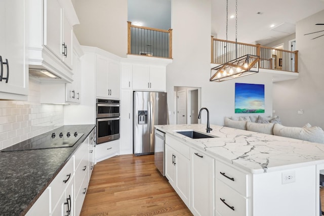 kitchen with stainless steel appliances, white cabinetry, a center island with sink, and sink