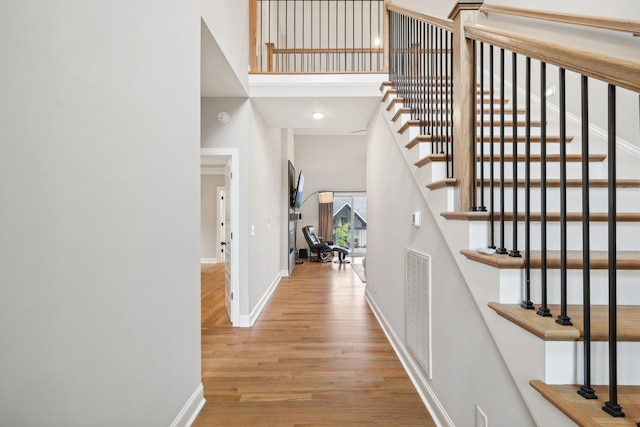 hallway with hardwood / wood-style flooring and a towering ceiling