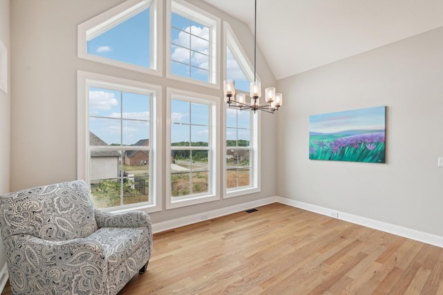 living area with high vaulted ceiling, an inviting chandelier, and light hardwood / wood-style flooring