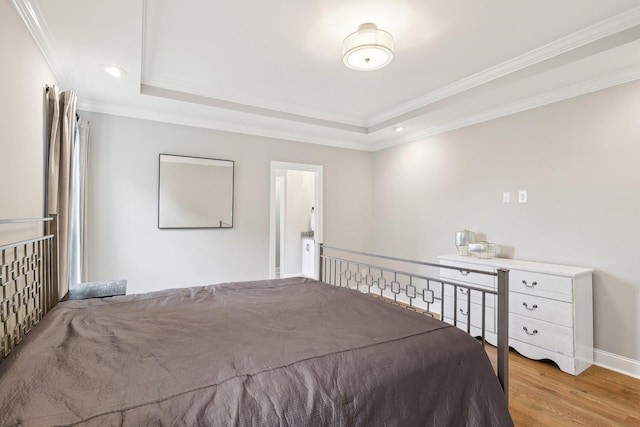 bedroom featuring light hardwood / wood-style flooring, a raised ceiling, and crown molding