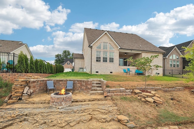 back of house featuring ceiling fan, a yard, and an outdoor fire pit