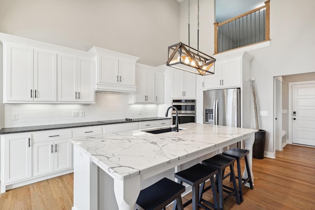 kitchen with white cabinets, appliances with stainless steel finishes, decorative light fixtures, and sink