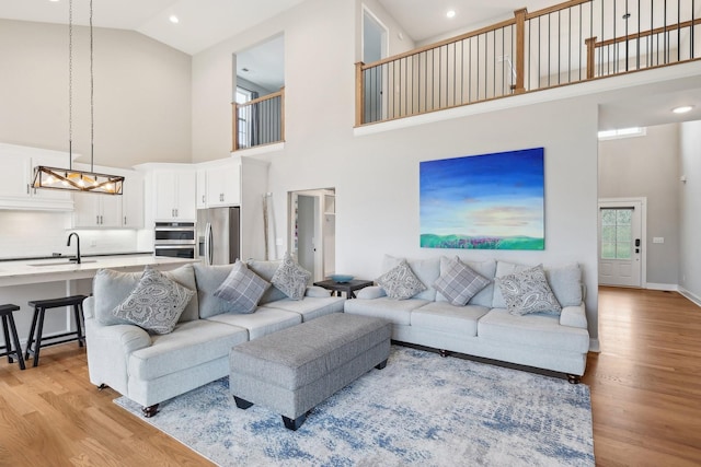 living room featuring a high ceiling, light wood-type flooring, and sink