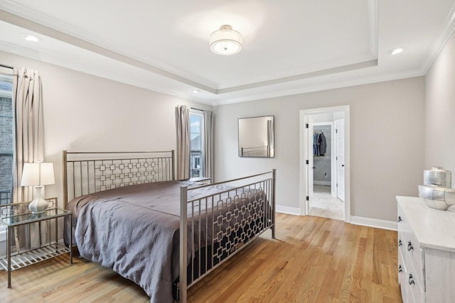 bedroom with a tray ceiling, ornamental molding, and light wood-type flooring