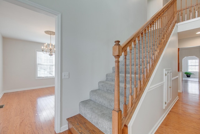 stairway with a notable chandelier and wood-type flooring