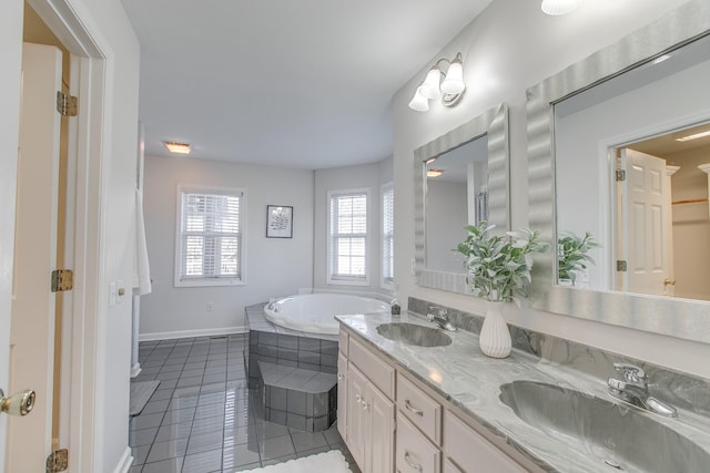 bathroom with tile patterned flooring, vanity, and a relaxing tiled tub