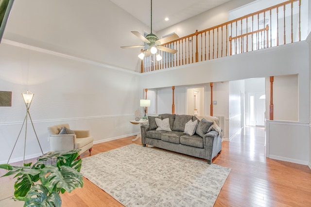 living room with ceiling fan, a towering ceiling, and hardwood / wood-style flooring