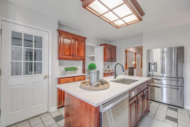 kitchen with light tile patterned floors, sink, stainless steel appliances, and an island with sink