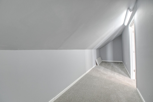 additional living space with light colored carpet and lofted ceiling