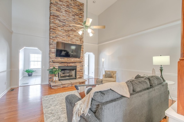 living room featuring ceiling fan, a fireplace, high vaulted ceiling, and wood-type flooring