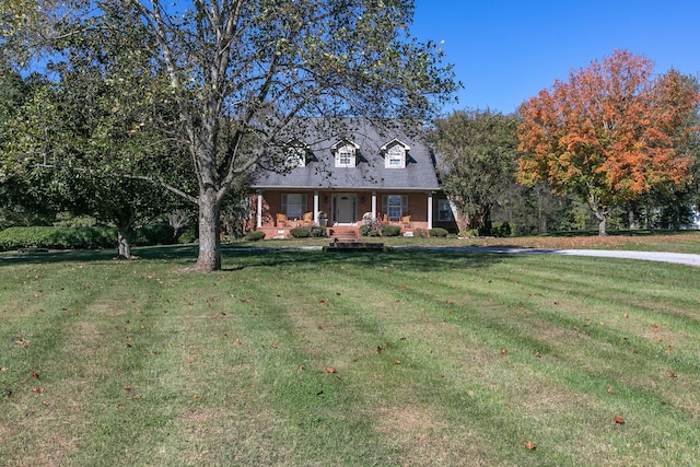 new england style home featuring a porch and a front lawn