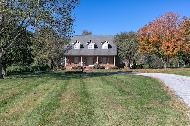 new england style home featuring a front yard and covered porch