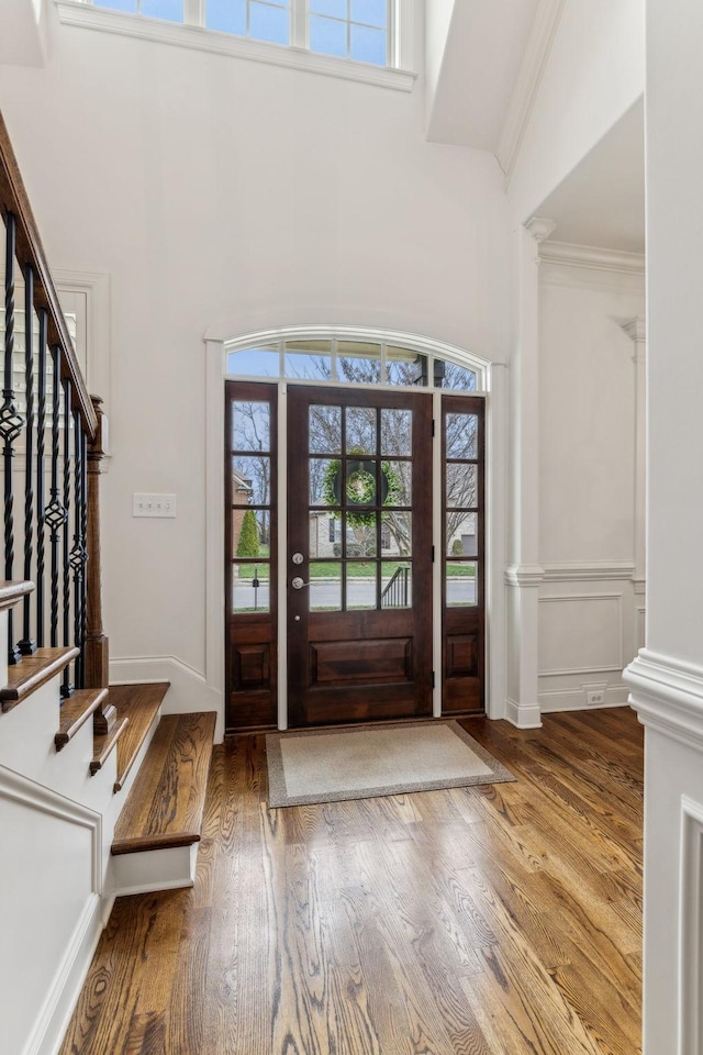 entrance foyer featuring a wealth of natural light, hardwood / wood-style floors, crown molding, and vaulted ceiling