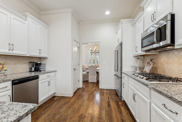 kitchen with light stone countertops, white cabinets, a notable chandelier, and appliances with stainless steel finishes